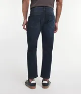 Pantalón de jean azul oscuro, corte slim, con trabillas en la cintura y bolsillos.