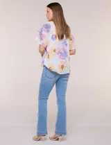 Blusa blanca de doble capa de gasa con estampado floral en tonos amarillos, celestes y rosados, escote en V con frunces y mangas cortas con volados amplios.