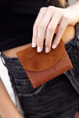 Billetera marrón de cuero con textura tipo cocodrilo en la parte inferior y solapa de gamuza en la parte superior.