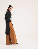 Pantalón de pana color verde oliva, de corte wide leg y largo al tobillo. Tiene cierre delantero con botón, bolsillos laterales y traseros.