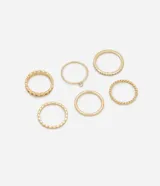 Set de seis anillos dorados de diferentes diseños: uno liso, uno con una piedra, uno con strass, uno retorcido, uno con textura de lunares y uno con textura de eslabones.