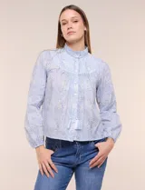 Blusa celeste de algodón con estampado floral, cuello mao fruncido con volado y cordel frontal con borlas. Tiene mangas largas abullonadas con puños elásticos y abotonadura frontal.