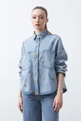 Sobrecamisa de denim color azul claro con bordados florales en tono marrón. Presenta cuello camisero, cierre frontal con botones metálicos y dos bolsillos de parche en el pecho.