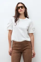 Remera blanca de algodón con cuello redondo y mangas cortas abullonadas con detalle de frunces.
