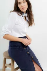 Falda midi de tiro alto confeccionada en pana color azul marino, con cierre frontal de botones y tajo delantero.