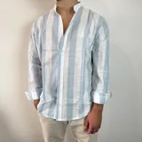 Camisa de manga larga con cuello mao, confeccionada en tejido de lino a rayas verticales en tonos blanco y celeste. Presenta cierre frontal con botones y corte clásico.