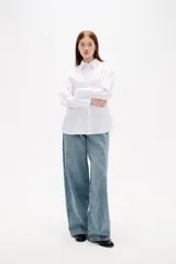 Camisa de algodón blanca con estampado de corazones formados por pequeños cristales de strass. Presenta cuello clásico, cierre frontal con botones, bolsillo en el pecho y mangas largas con puños abotonados.