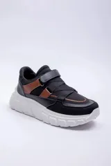 Championes deportivos para mujer modelo Pdk Vedra, en color negro con detalles en marrón tostado y suela chunky de color blanco. Presentan tiras cruzadas y cierre de velcro en la parte superior.