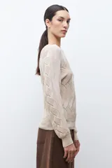 Sweater de punto color beige claro, con escote bote y tejido calado con diseño ondulado. Es de manga larga y corte recto.