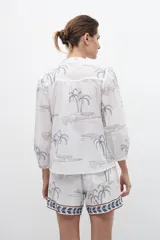 Camisa blanca estampada con palmeras y bordados en azul.