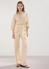 Jeans de corte recto y tiro medio en color beige claro, con diseño clásico de cinco bolsillos y presillas para cinto.