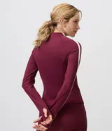 Campera deportiva Get Over en microfibra bordó, de ajuste próximo al cuerpo, con cuello alto, cierre frontal por cremallera y franja blanca contrastante desde los hombros hasta los puños.