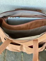 Mochila de cuero marrón con cierre superior y múltiples bolsillos externos. Se puede convertir en bolso de mano o bandolera gracias a sus correas ajustables y extraíbles.