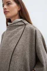 Ruana color crudo de lana fina sin teñir, con capucha, bolsillos y terminaciones envivadas. Tiene un broche para usar cerrada. Es una prenda oversize sin forro, cómoda, versátil y fácil de combinar.