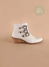 Botas cortas de cuero blanco con tres correas con hebillas plateadas y tachas. Taco de madera.
