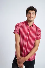 Camisa de manga corta con diseño a rayas verticales en color azul marino y blanco. Presenta cuello clásico, cartera abotonada frontal y logo bordado en el pecho. Posee un corte slim fit.