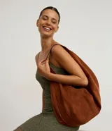 Cartera hobo Satinato de material sintético símil gamuza, color marrón, con diseño de media luna, cierre por cremallera y bretel ancho.
