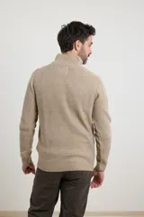 Sweater verde de punto inglés con cuello alto y cierre metálico frontal. Tiene mangas largas y terminaciones en punto canalé.