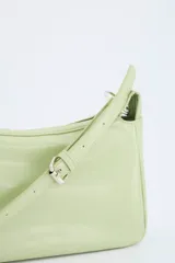 Bolso femenino color verde pastel, con diseño compacto y acabado tipo cuero. Incluye correa ajustable y un compartimento principal.