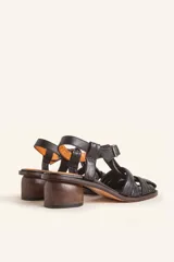 Sandalias de cuero color negro con diseño de tiras cruzadas tipo huarache, tira ajustable con hebilla metálica en el empeine y taco cilíndrico de madera.