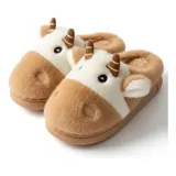 Pantuflas de peluche con diseño de vaca, confeccionadas en piel sintética suave. Cuentan con suela de goma antideslizante y diseño abierto en el talón.