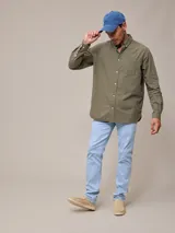 Camisa de manga larga para hombre, confeccionada en algodón con efecto peach (textura suave). Presenta un estampado de cuadros vichy en tonos azul marino y blanco, cuello con botones y un bolsillo de parche en el pecho izquierdo.