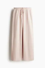 Pantalón tipo jogger de felpa en color rosado, con cintura elástica y cordón de ajuste. Presenta un corte holgado de pierna ancha y bolsillos laterales discretos.