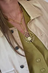 Collar de cadena de eslabones alargados con dije circular central que representa un sol estilizado, realizado en bronce con acabado dorado.