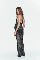 Top de cuello halter con lazada al cuello, escote en pico y bajo asimétrico. Confeccionado en tul con diseño de flores flocadas en contraste.