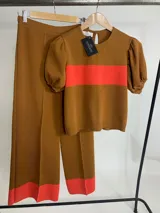 Conjunto tejido color marrón con detalles en naranja, compuesto por un sweater de mangas cortas abullonadas y pantalón de corte recto.