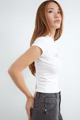 Remera de corte ajustado y manga corta, con cuello redondo y estampa frontal en tipografía cursiva. Confeccionada en tejido de punto elástico.