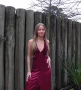 Vestido largo sin mangas con escote en V halter y aberturas laterales (cut-outs) en la cintura. El cuerpo superior presenta un llamativo diseño estampado multicolor, mientras que la falda larga es de tejido texturizado brillante en color verde esmeralda con inserciones godet en el ruedo.