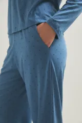 Pijama de dos piezas compuesto por una remera de manga larga con cuello redondo y un pantalón de corte recto y holgado. Ambas prendas presentan un estampado de pequeños puntos oscuros sobre una base de color azul.