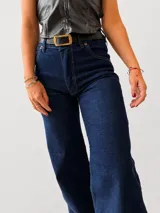 Jean de corte wide leg y tiro alto, confeccionado en denim azul oscuro. Presenta un diseño de pierna amplia y recta con costuras reforzadas en el ruedo.