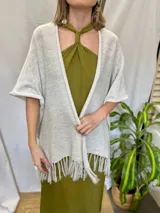 Ruana tejida color crudo con hilos plateados y flecos.