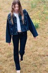 Jeans de denim color azul oscuro, tiro bajo, corte ajustado en muslos y acampanado desde la rodilla. Presenta cierre y botón frontal, bolsillos abiertos delanteros y bolsillos traseros con solapa y botón.