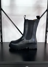 Botas Chelsea de caña media color negro, con elásticos laterales y suela track. Fabricadas en cuero vegano.