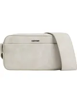 Bolso bandolera rectangular color beige de cuero sintético con acabado suave aterciopelado. Tiene correa ajustable, compartimento principal con cremallera, bolsillo exterior en la parte delantera, bolsillo interior y logotipo de Calvin Klein en la parte delantera.