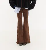 Jean de corte oxford con tiro medio, confeccionado en denim negro. Presenta recortes curvos en las piernas y detalle de botones metálicos en los laterales de la botamanga.