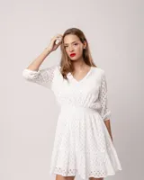 Vestido corto negro de broderie de algodón, con escote en V, mangas tres cuartos, cintura elastizada, falda corte A con volado y forro interior.