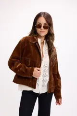 Campera de terciopelo color marrón chocolate, con cierre frontal, bolsillos laterales y elástico en el ruedo. Presenta un diseño de corte holgado con costuras marcadas.