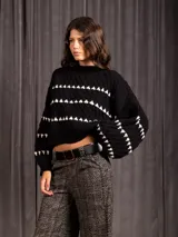 Buzo corto de tejido de punto en color negro, con diseño de textura en relieve y líneas horizontales blancas. Presenta cuello redondo y mangas largas con puños ajustados.