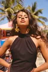 Vestido largo marrón de cuello halter con espalda descubierta, tajo lateral pronunciado y detalle de volados con flecos en el frente.