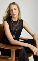 Musculosa de punto negro Le Lis Blanc, de corte recto, escote redondo, sisas amplias y tejido calado con transparencia. Presenta un diseño asimétrico con superposición frontal y detalle de anillo metálico en el lateral.