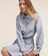 Vestido corto chemise de algodón con estampa a rayas celestes y blancas, cuello solapa, manga larga, abotonado frontal y cintura marcada con falda evasé con pliegues.