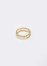 Anillo dorado de acero quirúrgico con diseño de contorno y detalle de strass.