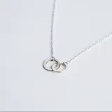 Collar de plata 925 con cadena fina y dije compuesto por dos aros entrelazados de diseño minimalista.