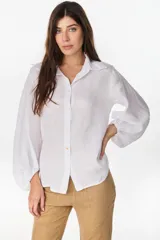 Camisa de lino italiano con estampado a rayas verticales irregulares, de corte holgado, cuello clásico, mangas abullonadas y cierre frontal con botones.