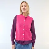 Chaleco sin mangas de punto suave en color fucsia, con escote en V y cierre frontal de botones blancos.