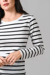 Remera de manga larga con diseño a rayas horizontales en color crudo y negro, con cuello redondo.